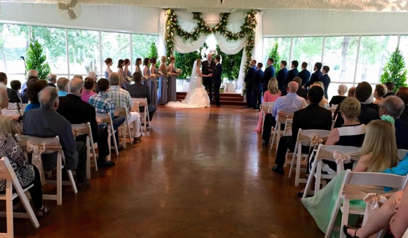 Taking their vows adorned with flowers at an indoor wedding at House Estate