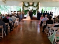 Taking their vows adorned with flowers at an indoor wedding at House Estate